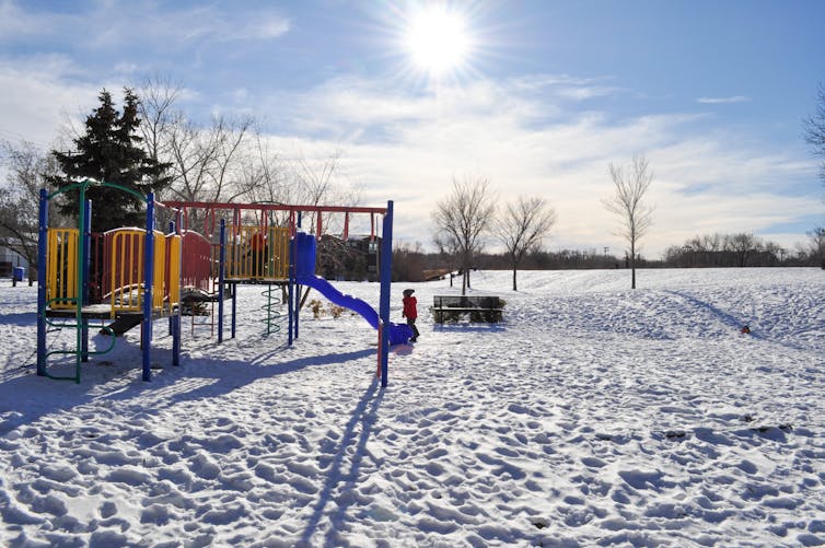 A child at a playground in winter.