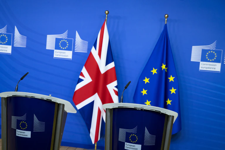 Two empty podiums in front of a Union flag and a European flag.