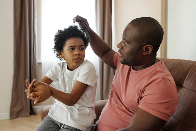Un père coiffant son enfant. Photo d’illustration.