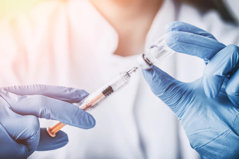 A medical professional loading a syringe with liquid vaccine