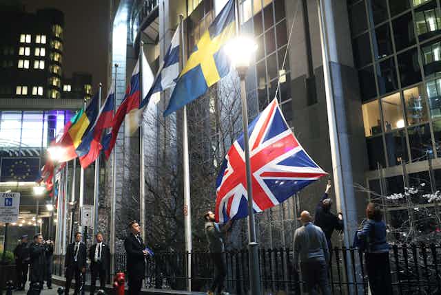 Staff removing the Union Flag from outside the European parliament. 