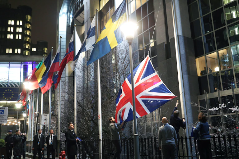 Staff removing the Union Flag from outside the European parliament.