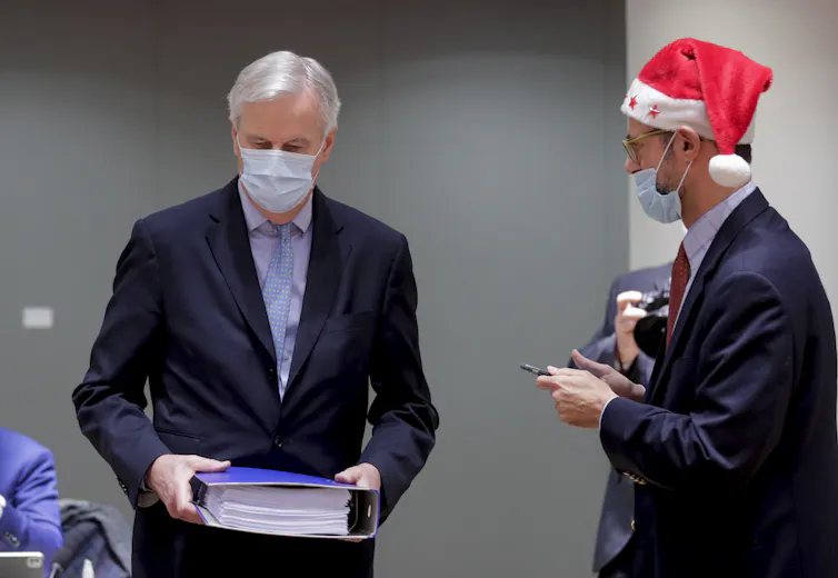 Michel Barnier holding a large binder containing the post-Brexit trade deal.