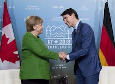 Angela Merkel and Justin Trudeau shake hands.