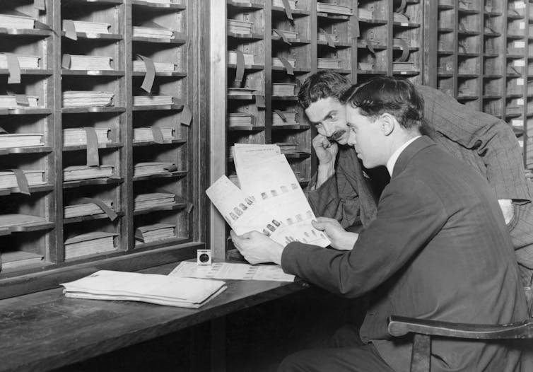 Scotland Yard detectives comparing fingerprints