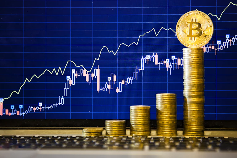 Bitcoin coins stacked in front of an upwards trending line graph.