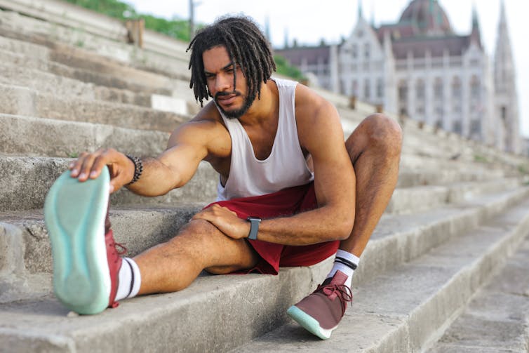 A man in running clothes stretching his leg