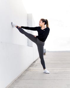 A woman in workout clothes stretching her leg