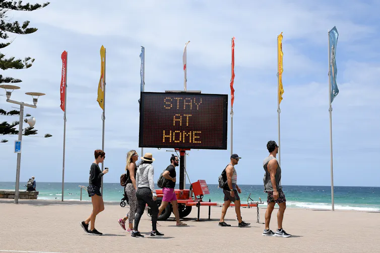 Sign on Manly Beach advising people to stay home