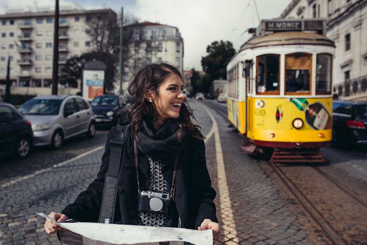 Woman with map in front of tram in city