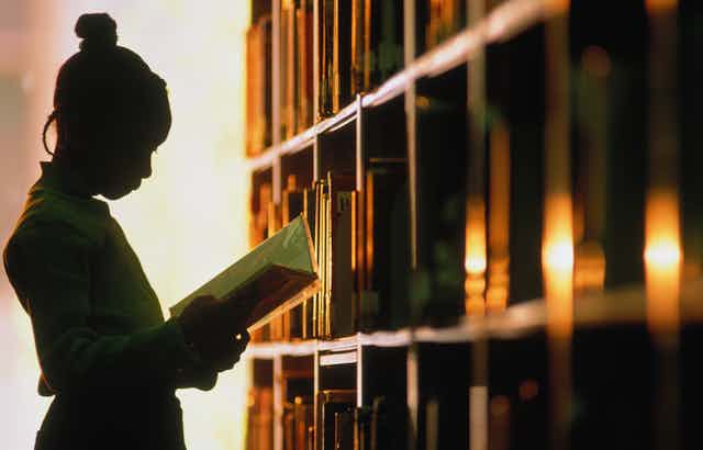 A Black woman reading in a library