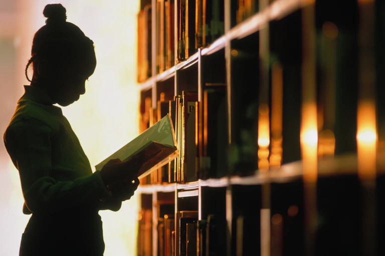 A Black woman reading in a library