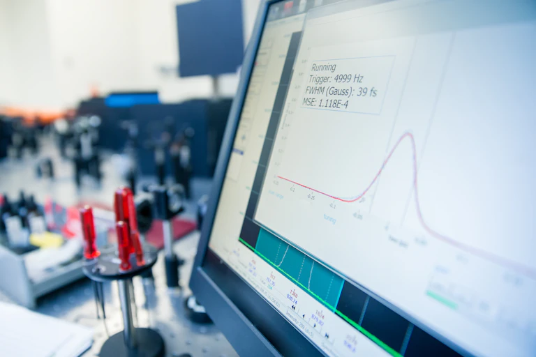 A computer monitor showing a bell curve graph with scientific instruments in the background.