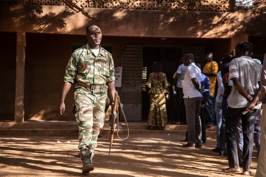 Un militaire et des électeurs devant un bureau de vote à Ouagadougou