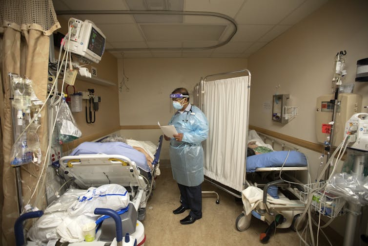 A doctor talks with patients in a cramped, temporary room