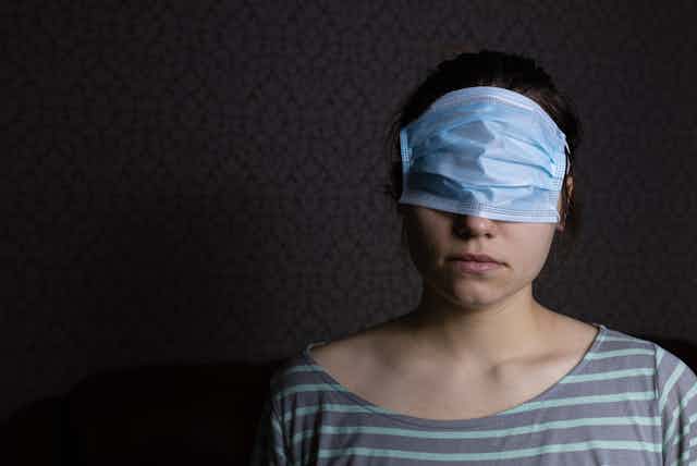 A woman wearing a surgical mask over her eyes