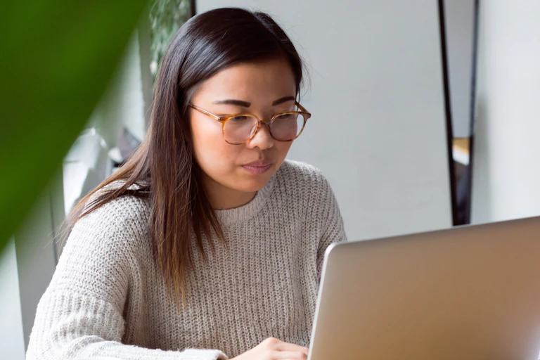A woman sits at her laptop.