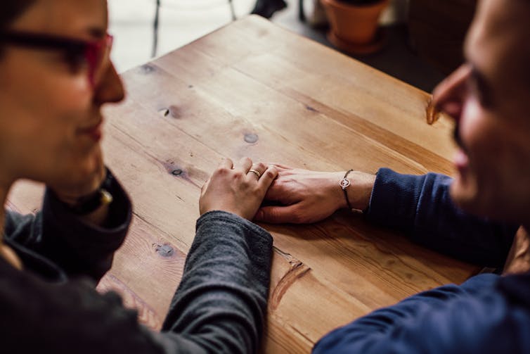 Two people hold hands at a table.