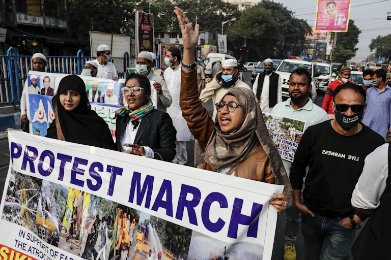 Three women carry a banner during a protest.
