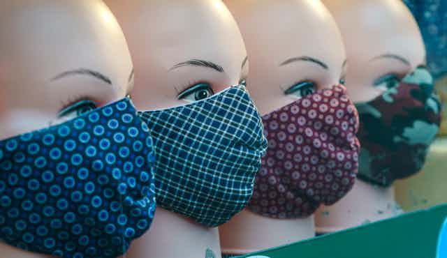 Face masks on mannequins in a shop window.