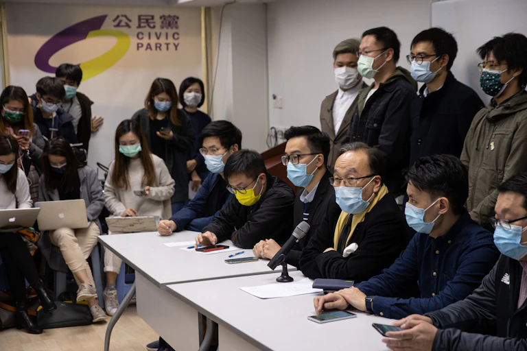 Row of Hong Kong politicians sit in front of journalists for press conference.