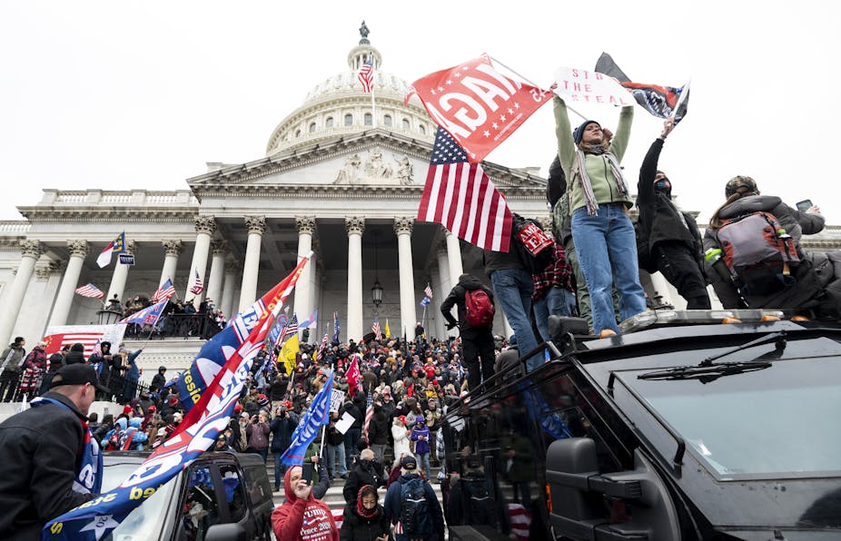 Trump supporters waving Trump and Confederate flags on the steps of the Capitol Building
