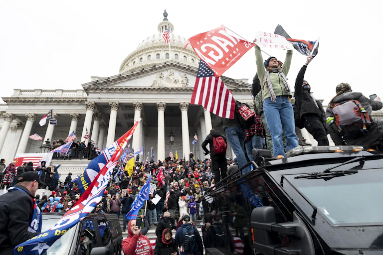 Trump supporters waving Trump and Confederate flags on the steps of the Capitol Building