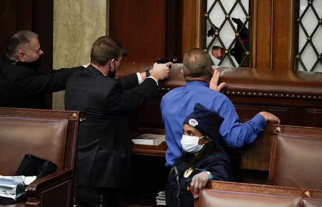 Security guards pull their guns on a protester who is outside of the House chamber