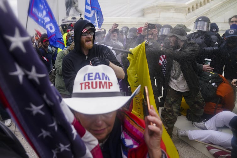 A protester with a white Team Trump cowboy hat leads protesters