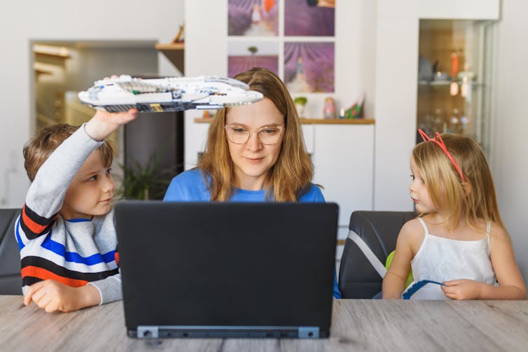 woman trying to concentrate on work while being distracted by two children