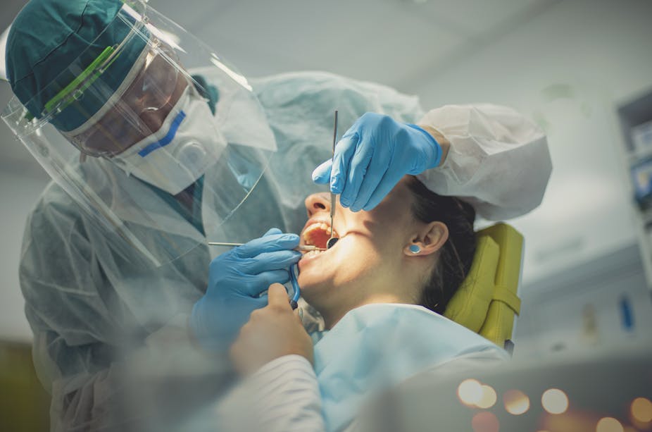 A dentist examines the mouth of a patient.