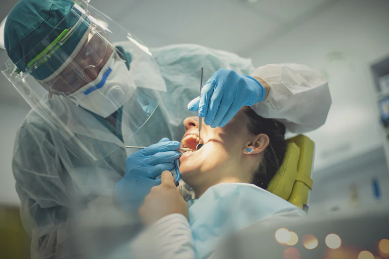 A dentist examines the mouth of a patient.