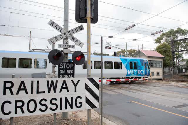 a train travels through a level crossing with the boom gates down