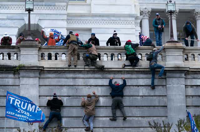 Protesters climbing a wall into Capitol building