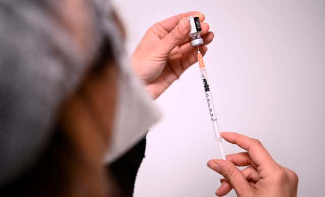 Health worker fills a syringe with Pfizer' COVID vaccine