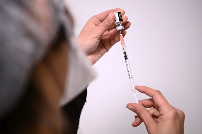 Health worker fills a syringe with Pfizer' COVID vaccine