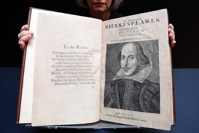 Person holding William Shakespeare's First Folio open towards the camera