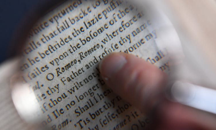 Person’s finger on magnified page of Shakespeare’s Romeo and Juliet, reading: