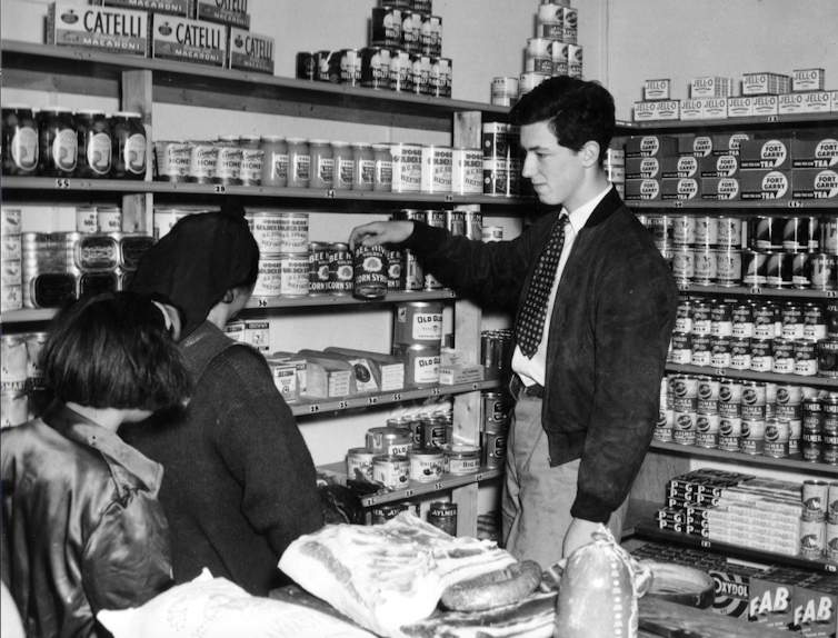 A young man in a shop with two female customers.