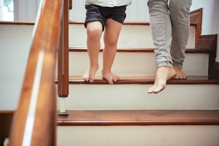 Two people's feet as they climb downstairs.