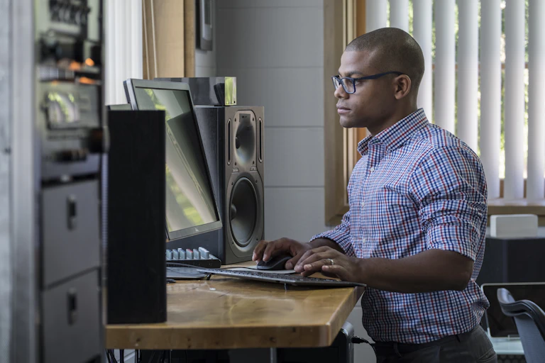 Man standing at his desk while working on his computer.