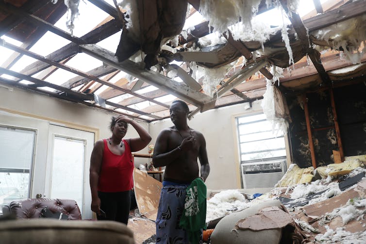 Latasha Myles and Howard Anderson stand in the living room where they were sitting when the roof blew off