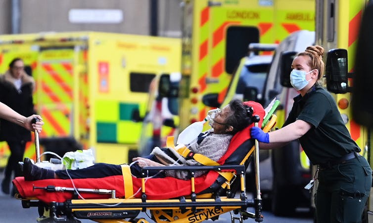 A paramedic transporting a patient on a stretcher from an ambulance into hospital.