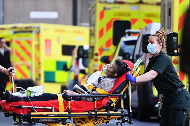A paramedic transporting a patient on a stretcher from an ambulance into hospital.