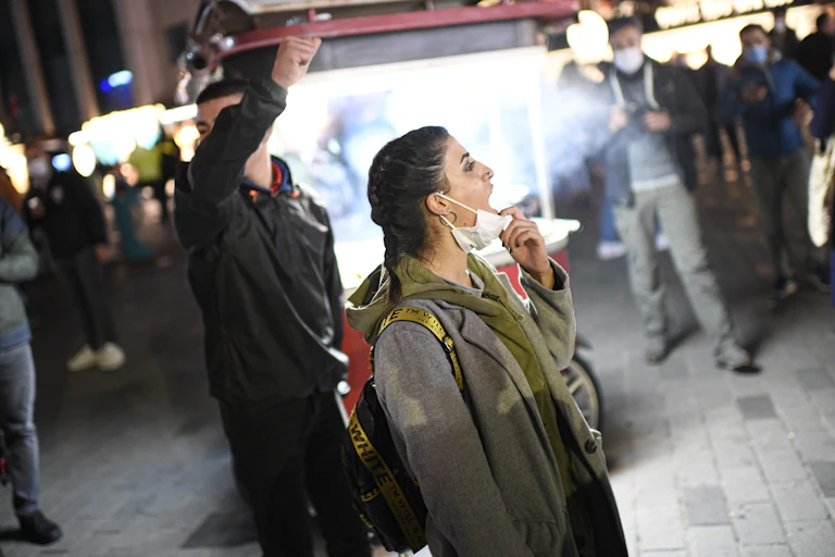A woman pulls down her face mask to chant slogans