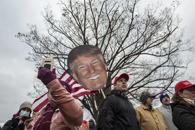 MAGA crowd marches with cardboard cutout of Trump's face