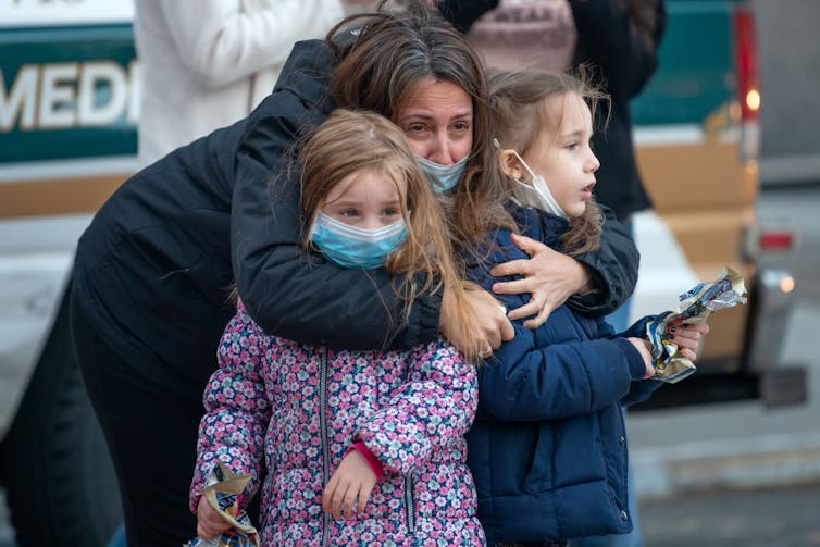 A women hugs two young girls.