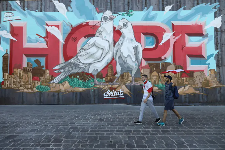 People walk past a wall mural of hope.