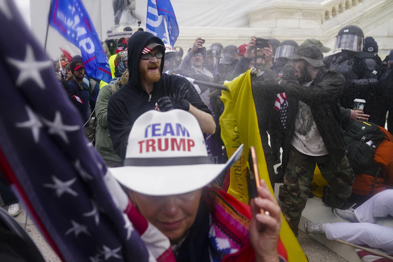 A chaotic scene as security police clash with protesters, including a woman wearing a white Team Trump cowboy hat