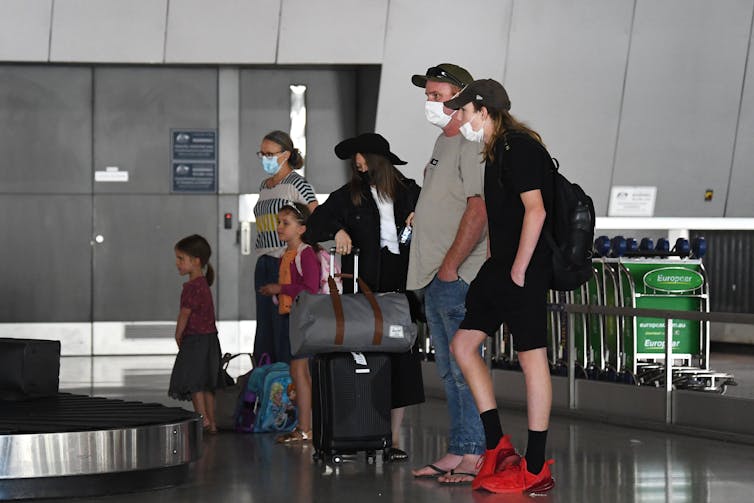 Family at baggage carousel wearing masks